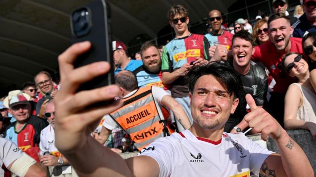 Marcus Smith takes a selfie with travelling fans after Harlequins' Champions Cup match away to Bordeaux-Begles in 2024